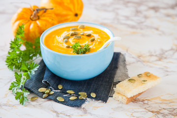 pumpkin cream soup on a table with ingredients, selective focus, copy space
