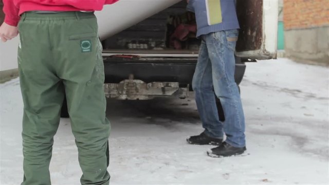 People unload a car drywall/two people unloading truck with plate drywall