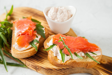 cheese, red fish and arugula sandwich on a board, selective focus, copy space