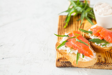 cheese, red fish and arugula sandwich on a board, selective focus, copy space