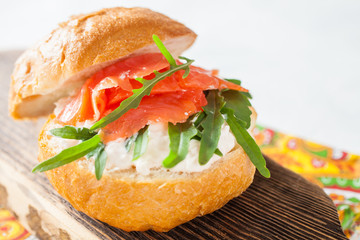 cheese, red fish and arugula sandwich on a board, selective focus, copy space