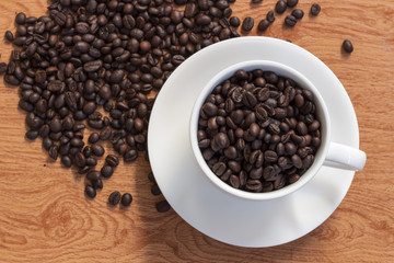 Coffee cup and coffee beans on wooden background. Top view.