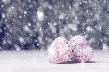 Fototapeta premium Two hearts in snowfall over abstract background