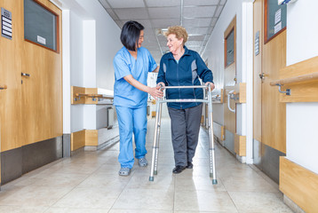 Senior female patient being assisted by female asian nurse in us