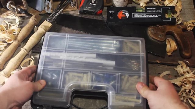 Video of a carpenter table upper view with hand placing plastic organizer box.