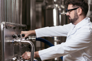 Delighted man making beer in brewery