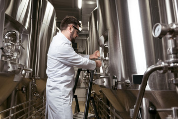 Concentrated man using ladder in brewery