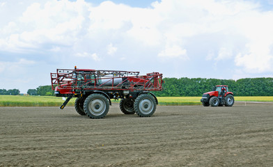 Fototapeta premium Сельскохозяйственный опрыскиватель и трактор на поле