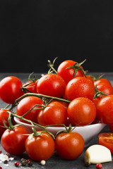 Cherry tomatoes on branch and spice on a dark background.