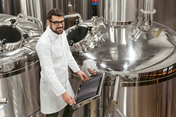 Delighted man using computer at beer factory