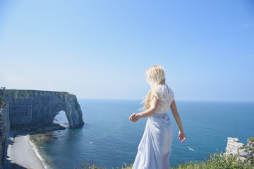 Girl with blond hair in dress on the edge of the cliff into the sea in the north of France - Powered by Adobe