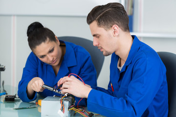 team of students examining and repairing computer parts