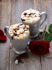 S'mores drink. Two mugs of hot chocolate with marshmallows on a wooden table. Cocoa. Rose petals. Valentine.