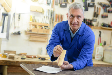 senior carpenter sanding plank in his workshop