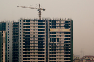 Fototapeta na wymiar Under construction buildings with a crane and concrete structure in Noida Delhi Gurgaon. The surge in people living in these cities has led to huge construction projects