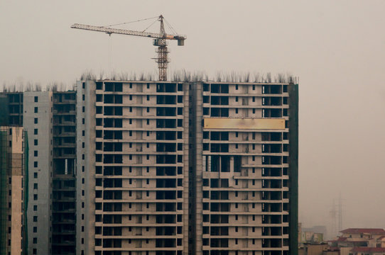 Under construction buildings with a crane and concrete structure in Noida Delhi Gurgaon. The surge in people living in these cities has led to huge construction projects