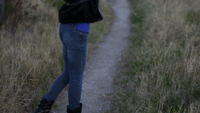 Jeans blu di una ragazza su una stradina di campagna 