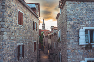 Old city street with ancient building facades during beautiful sunset with dramatic sky