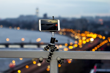 The smartphone is fixed on a tripod shooting a video