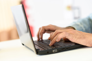 Hands of a man typing with a laptop computer