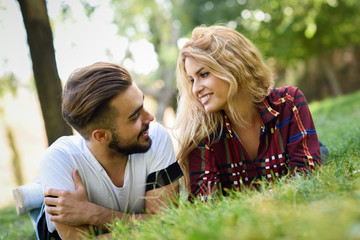 Beautiful young couple laying on grass in an urban park.