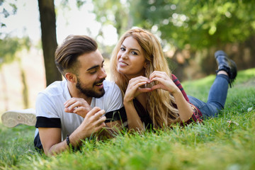 Beautiful young couple laying on grass in an urban park.