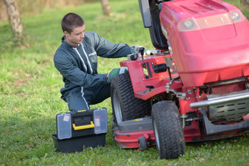 Young man repairing ride on mower