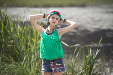 Attractive beautiful blonde girl in shorts and a headband walks and posing in the Park in the nature near the water. Perfect makeup and beautiful Oriental look