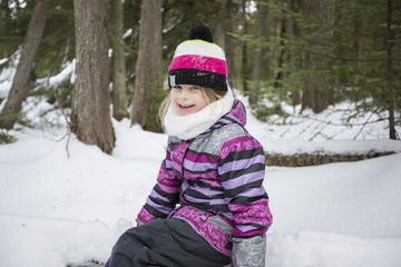 Obraz premium Little girl in winter pink hat in snow forest.