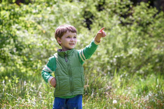 Five year old boy looking and pointing his finger at the strange tree.