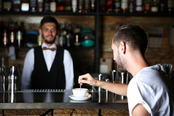 Man with cup of coffee at bar counter