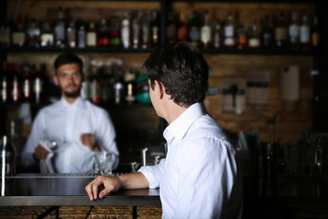 Man in white shirt sitting at wooden bar counter