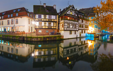 Panorama of traditional Alsatian half-timbered houses with mirror reflections in Petite France during twilight blue hour, Strasbourg, Alsace, France