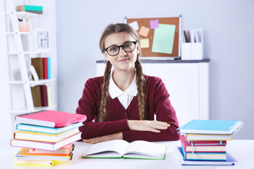 Teenage girl with pile of books sitting at desk in a classroom © Africa Studio