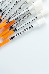 Three insulin syringes isolated on white background. Pile of Medical syringes. Single insulin syringe with orange cap.