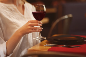 Closeup of woman holding glass of red wine in cafe