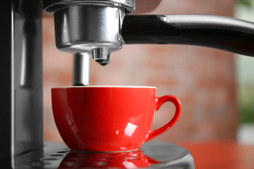 New electric coffee maker with red cup, close up