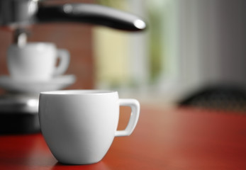 Cup of fresh espresso and new coffee maker on table