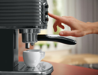 Female hand pushing button on electric coffee maker, closeup