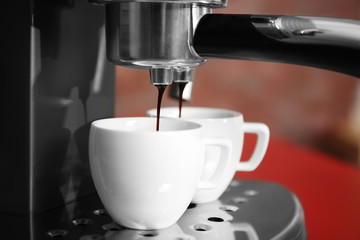 New coffee maker pouring fresh espresso into two cups, closeup