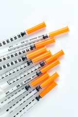Three insulin syringes isolated on white background. Pile of Medical syringes. Single insulin syringe with orange cap.