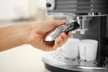 Woman making fresh espresso with electric coffee machine