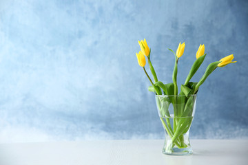 Glass vase with bouquet of beautiful tulips on color background