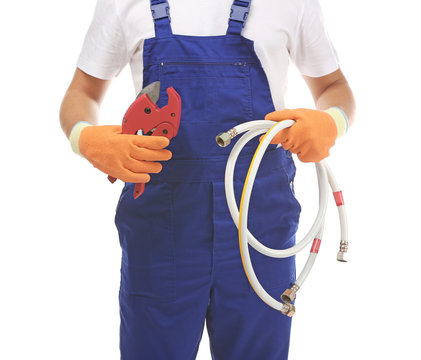 Young handsome plumber with cutter and flexible hose on white background