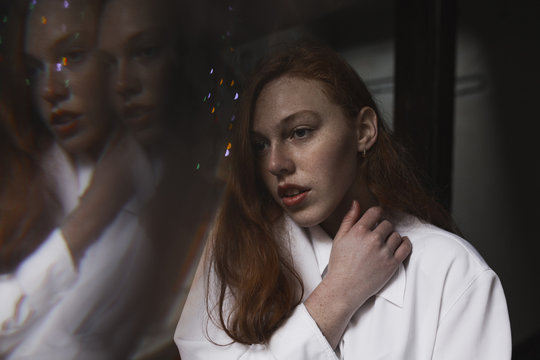 Tender redhead woman with her reflection on a background