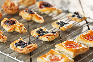 Sweet tasty pastries on baking grid against wooden background