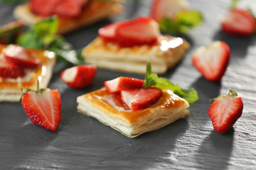 Sweet tasty pastries with fresh strawberries on textured background