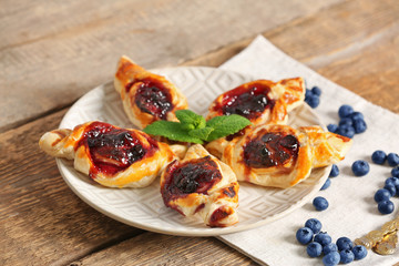 Sweet tasty pastries and fresh bilberries on wooden background