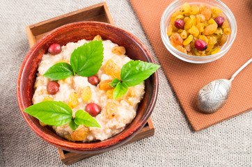 Top view of oatmeal with raisins, berries and herbs