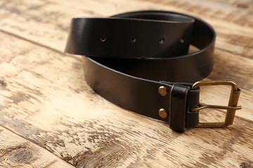 Stylish leather belt on wooden background